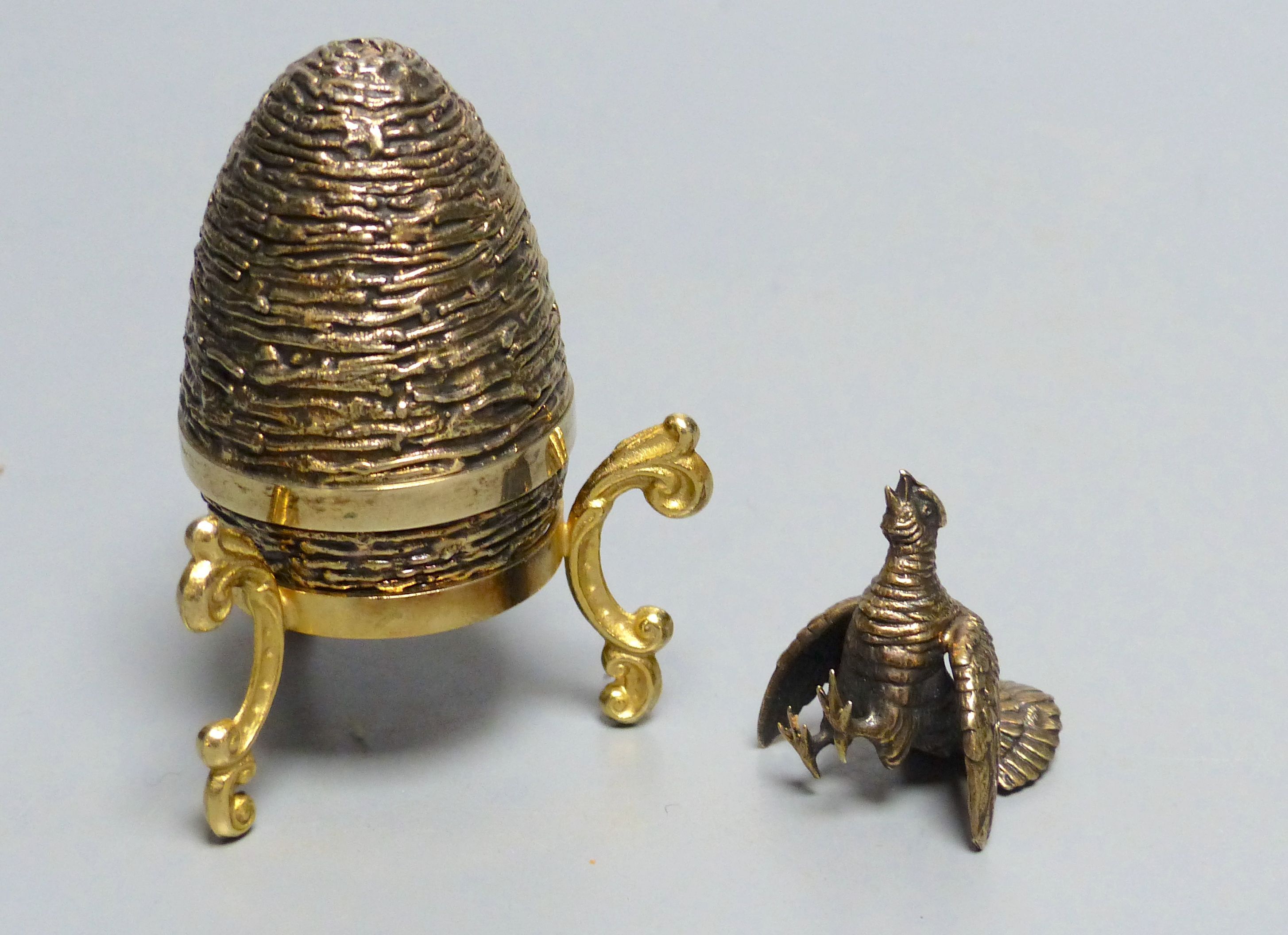 A modern silver gilt surprise egg, by Richard Lawrence Geere, London, 1975, on stand & a model of a fighting cock.